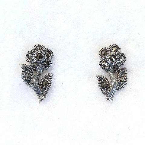 A curved stem features a leaf on each side and a flower top. Each earring features seven marcasite stones.